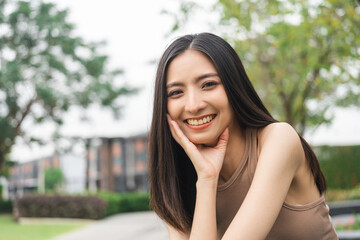 Happy feeling of Beautiful Young Woman smiling outdoor in sunlight. Pretty attractive face of female and beautiful smile. She is positive thinking and successful.