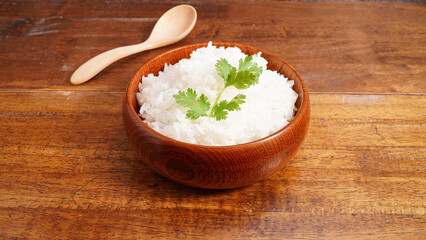 Hot cooked rice in brown wooden bowl