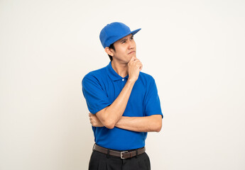 Happy delivery asian man in blue uniform standing thinking on isolated white background. Smiling male delivery service worker. Courier and shipping service.