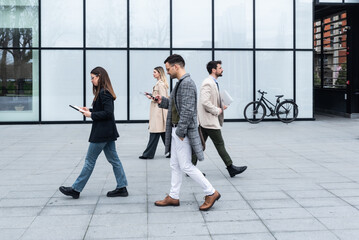 Think different concept. Group of business people in front of office building one business person walking in opposite direction from other employees. Be independent different stand out from the crowd