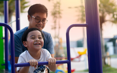 Obraz premium Playtime. Asian father smiling while playing with his son at playground outdoors.