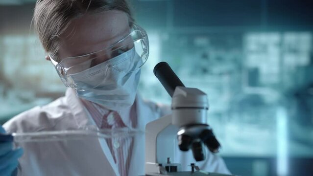 Medical science laboratory. A microbiologist wearing glasses is looking under microscope analyzing sample. Scientist pharmacist working with forensic. Genetic dna research and pharmaceutics concept