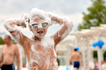 Face of a child in foam enthusiastic joyful child at a foam party, close-up of a child among the...