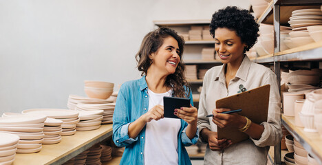 Two happy female ceramists working together in their shop - Powered by Adobe