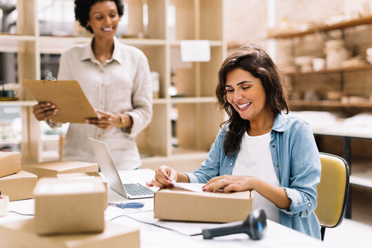 Happy young businesswoman preparing an online order for shipping in a warehouse