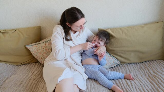 A mother woman sucks a runny nose from a baby with a snot pump. Mom cleans child's nose with a snot pump Kid aged about two years (one year nine months)