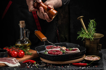 male hands holding beef meat on a dark background, Whole piece of tenderloin with steaks and spices ready to cook, Long banner format