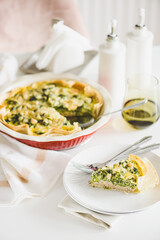 Quiche. Healthy homemade chicken pie with broccoli and spinach on white wooden table
