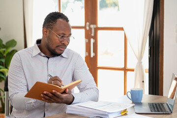 African black businessman sitting doing a financial report and studying annual profit analysis An accountant checking the financial status of the company is in the office.