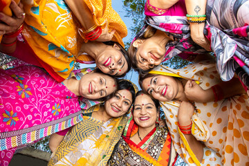 Group of happy young traditional indian women wearing colorful sari looking down and embracing each other like a team. Rural india. women empowerment.
