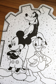 Disney coloring magazine. Mickey Mouse, Goofy and Donald Duck in their classic outfits. White background and black lines.