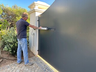 Man inspecting the hydraulic ram on an electric gate opener