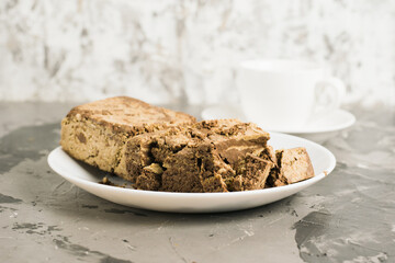 Delicious halva with cocoa on a white plate on a light gray concrete background