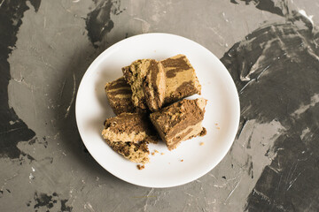 Delicious halva with cocoa on a white plate on a light gray concrete background