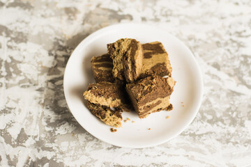 Delicious halva with cocoa on a white plate on a light gray concrete background