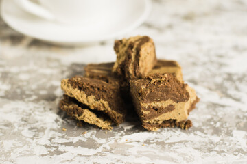 Delicious oriental sweets, halva with cocoa and coffee in a white cup on a gray concrete background