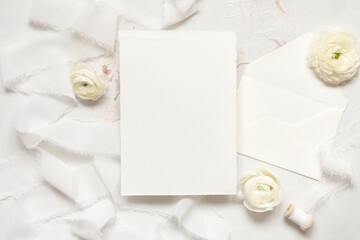 Blank card near cream roses and white silk ribbons, top view, wedding mockup