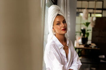 Portrait of beautiful woman wearing white shirt and turban towel on head while daydreaming at the wall