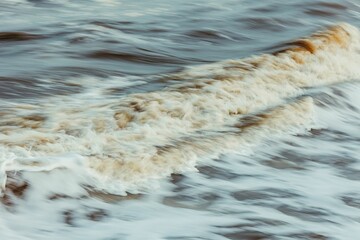 Beautiful shot of large brownish foamy waves crashing onto the shoreline, perfect for wallpapers