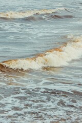 Beautiful shot of large brownish foamy waves crashing onto the shoreline, perfect for wallpapers
