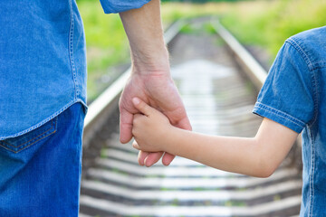 A Hands of a happy parent and child in nature in the travel park