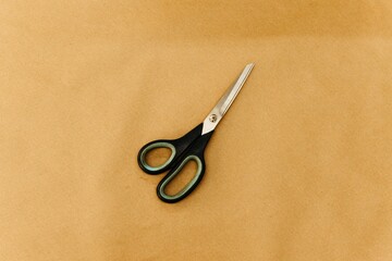 scissors sitting on top of brown paper on a table and on the ground