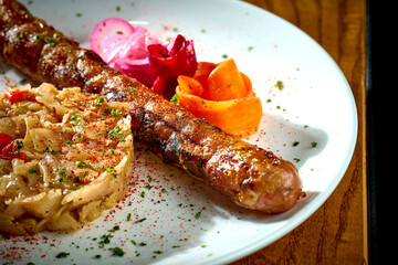 Bavarian meat sausage with a garnish of stewed sauerkraut, onions in a plate on a wooden background