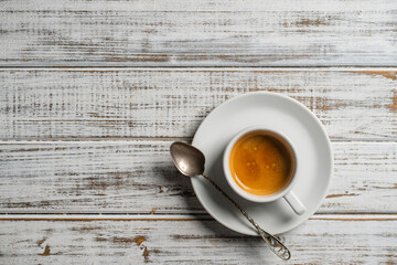 White porcelain coffee cup with saucer and spoon over wooden background, top view, copy space,...