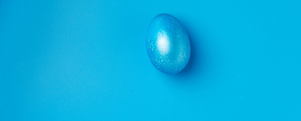 Easter background with blue Easter eggs and spring flowers on a blue background. Top view, space for text, banner