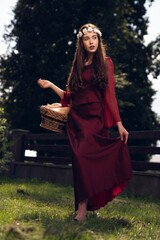 Beautiful young girl with a straw basket posing outdoors