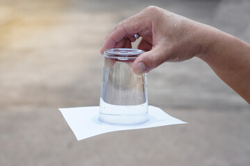 Closeup hand hold and turn  a glass of water over down. covered the glass with paper. Concept, ...