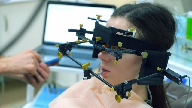 Orthodontist is doing condylography procedure to woman patient. Examination and treatment of mandibular joints. Orthodontology treatment and cure concept. Dentistry and clinic.