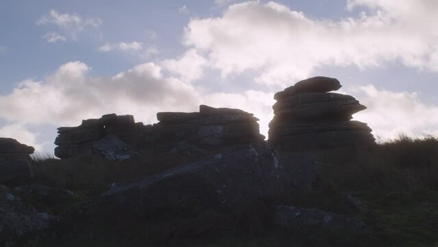 Footage of white clouds moving in the sky with rocks in the foreground in Dartmoor, Devon, England