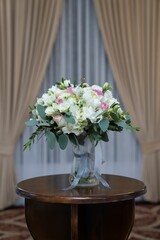 bouquet of flowers sits on a table in the room between two drapes