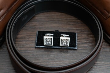 Closeup of silver cufflinks on a wooden table.