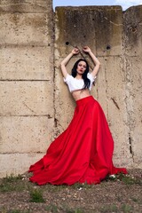 a beautiful asian woman in long red skirt posing in front of a wall