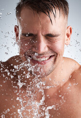 Fototapeta premium Cleanliness is next to godliness. Studio shot of a handsome young man washing his face against a grey background.