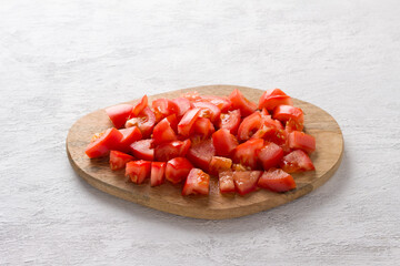 Wooden board with sliced tomatoes on a light gray background. Cooking delicious homemade food