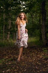 Young female in a beautiful floral dress posing running in a forest