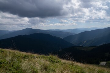 an open valley with tall grass on top and mountains in the distance