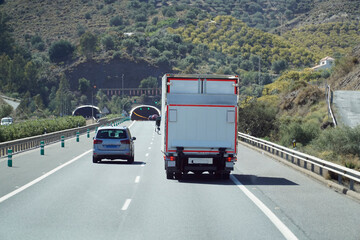 Fototapeta na wymiar Truck on a highway - back view, tunnel through mountain