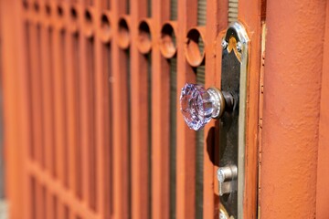 Closeup shot of a metal gate with a glass knob.