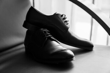 Grayscale shot of a pair of shoes, resting on a flat surface in a minimalist setting.