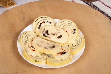 Closeup of a plate with cheese roll-ups on the wooden tray.
