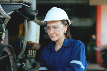 A female engineer wearing  uniform with a white hat. Remote monitoring and control of robotic arm welding machines in industrial plants.