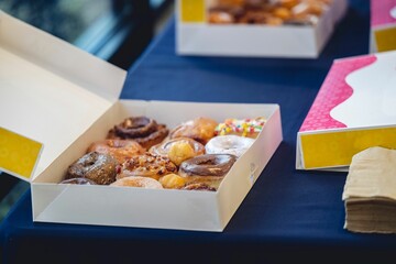 Assortment of freshly baked doughnuts on the tabletop, sprinkled with sugar and other toppings.