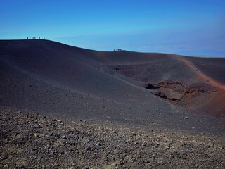 a barren mountain in the distance, some people walking on top
