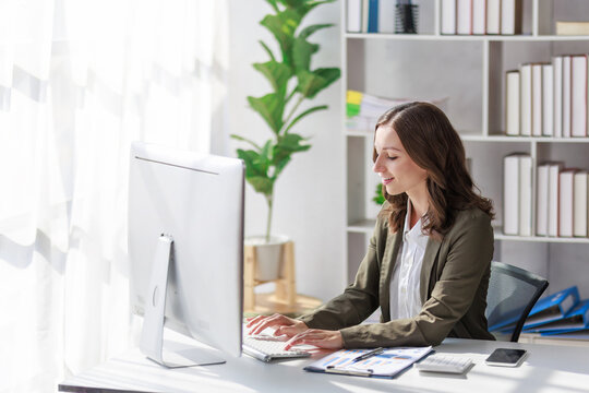 Concept of business investment or working woman,  Businesswoman wearing a suit sitting and working on analysis of business investment documents and using computer to analytic business data.