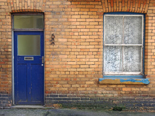 Fototapeta na wymiar front view of a typical old small english terraced brick house with blue painted door and window