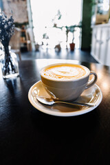 Coffee cappuccino in cup on wooden table in cafe